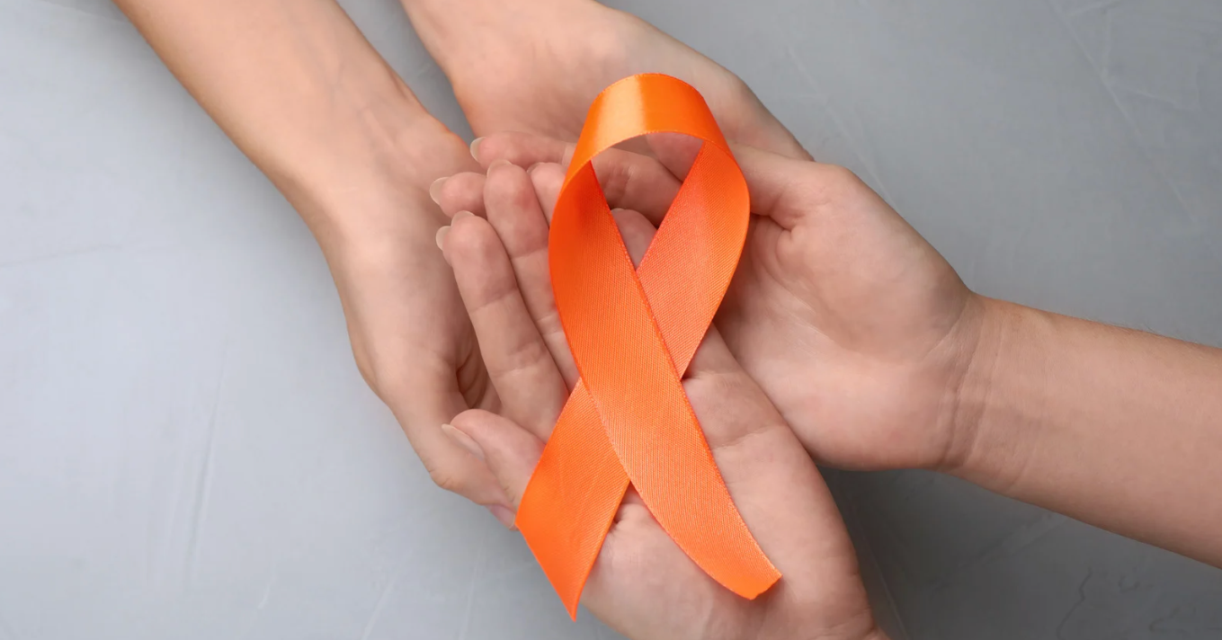 มือสองคู่ประคองริบบิ้นสีส้ม สัญลักษณ์ให้กำลังใจผู้ป่วยมะเร็งและการรณรงค์ต้านโรคมะเร็ง